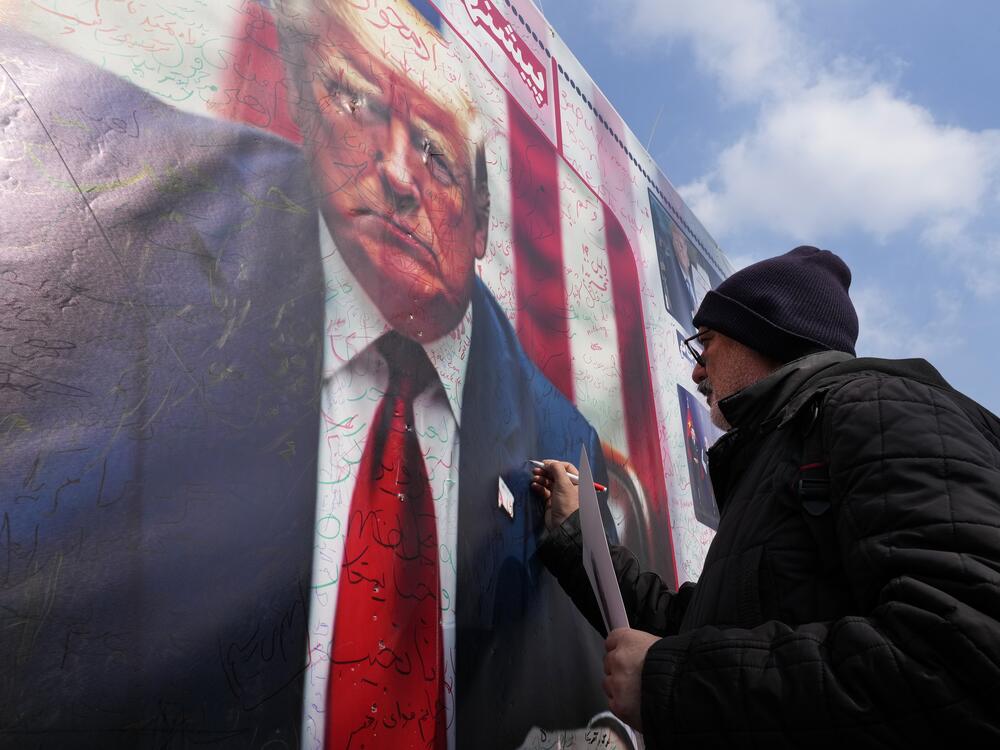 A man writes a slogan on a portrait of the U.S. President Donald Trump during a rally commemorating anniversary of Iran's 1979 Islamic Revolution that toppled the late pro-U.S. Shah Mohammad Reza Pahlavi and brought Islamic clerics to power, in Tehran, Iran, Monday, Feb. 10, 2025. Trump says the US and Iran will have direct nuclear talks soon.