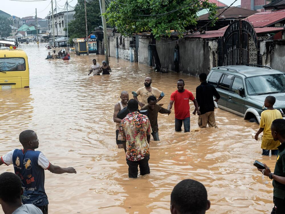 People walk through the flooded streets of Kinshasa, Democratic Republic of Congo on Sunday.