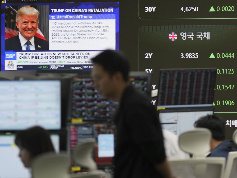 Currency traders watch computer monitors near the screen showing news reporting with a picture of President Donald Trump at a foreign exchange dealing room in Seoul, South Korea on Tuesday.