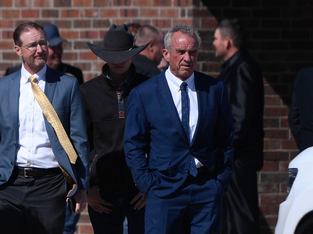 Health and Human Services Secretary Robert F. Kennedy Jr., right, arrives at Reinlander Mennonite Church after a second measles death of a child, on Sunday in Seminole, Texas.