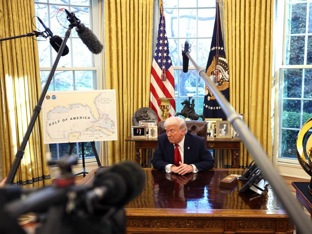 President Trump speaks to the press in the Oval Office next to a map of what he has renamed the 