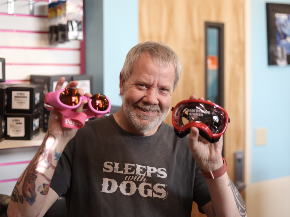 Mark Robokoff, the owner of AK Bark in Anchorage, shows the two models of eye protection available at his pet store.