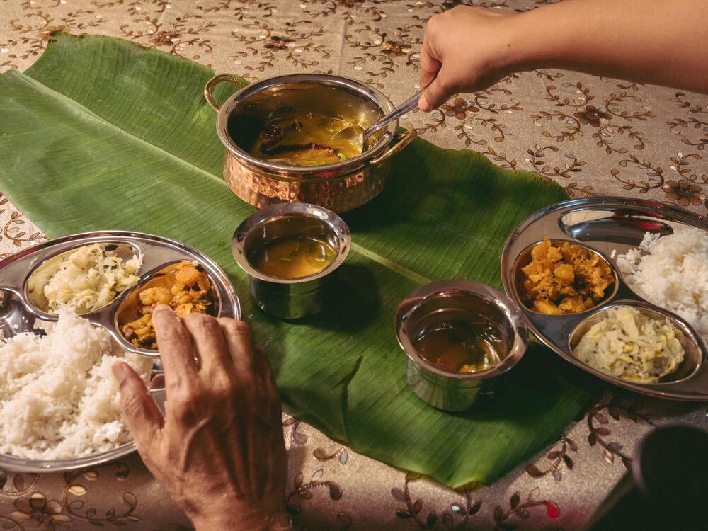 The photographer's father and elder sister pictured with <em>thakkali rasam</em> — or tomato <em>rasam</em> — prepared by her mother, Puvaneswari Kannusamy, from a recipe passed on through generations. <em>Rasam</em> can be eaten on its own or combined with rice and vegetables.