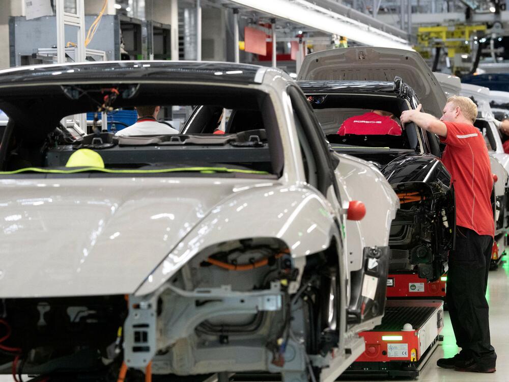 Employees of German car producer Porsche AG work on Porsche Taycan electric sports cars at the assembly line of the Porsche production site in Stuttgart, southwestern Germany in 2022.