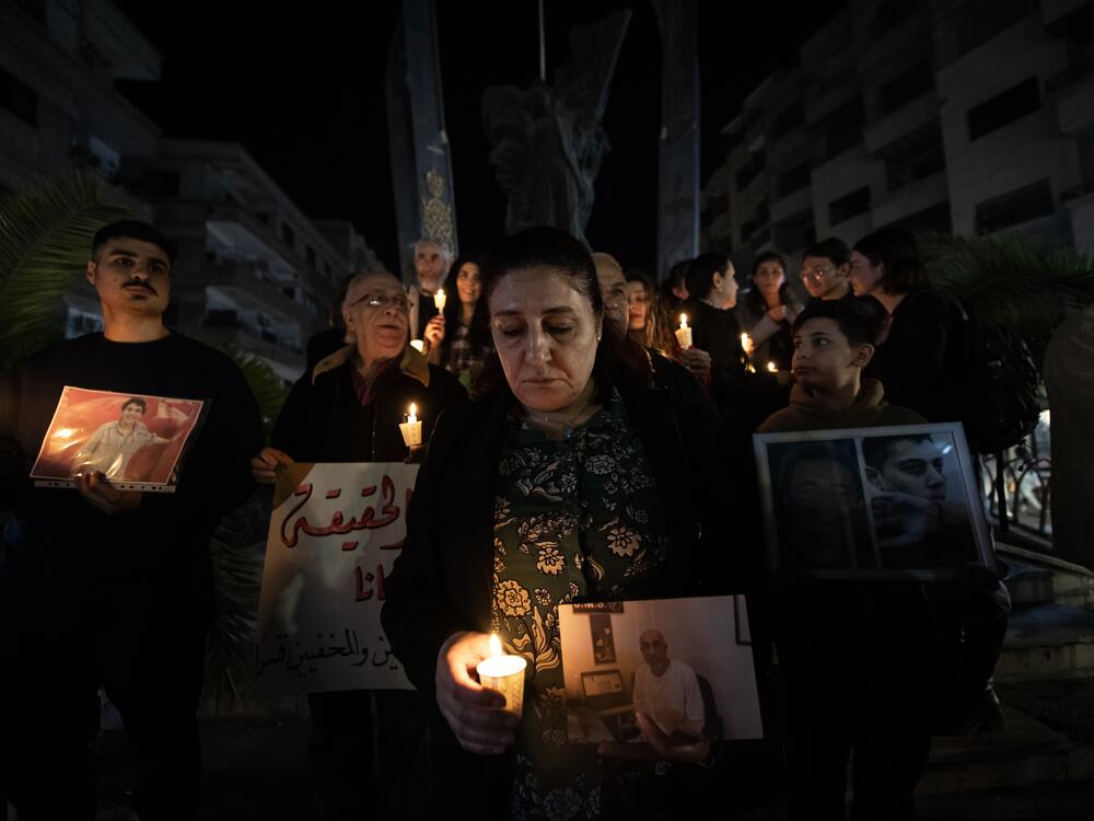 Majida Kaddo holds a photo of one of her missing relatives and a candle at a vigil in Damascus on March 27.
