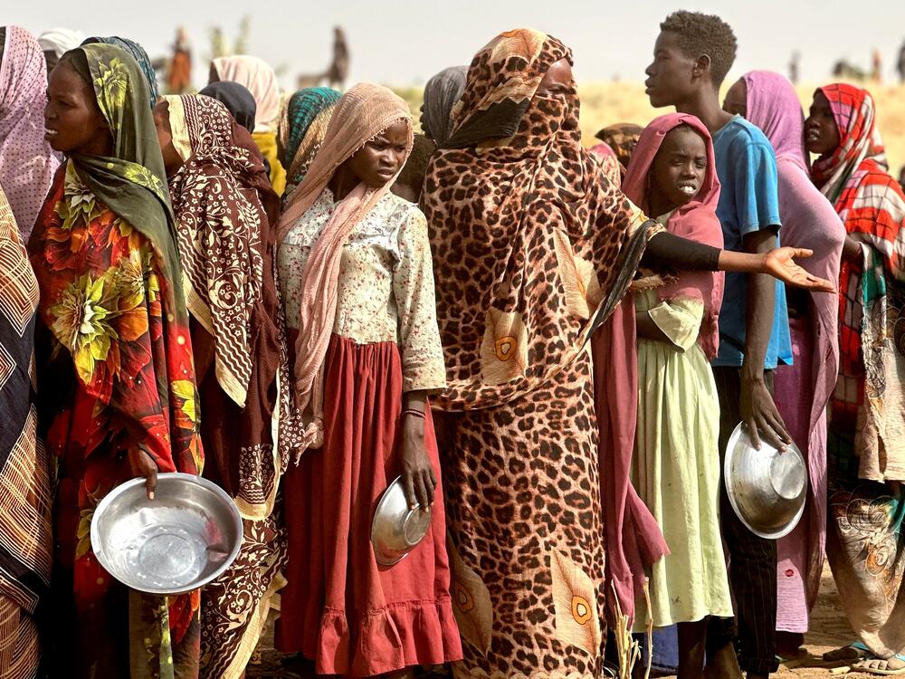 People who fled the Zamzam camp for the internally displaced after it fell under RSF control, queue for food rations in a makeshift encampment in an open field near the town of Tawila in war-torn Sudan's western Darfur region on April 13, 2025.