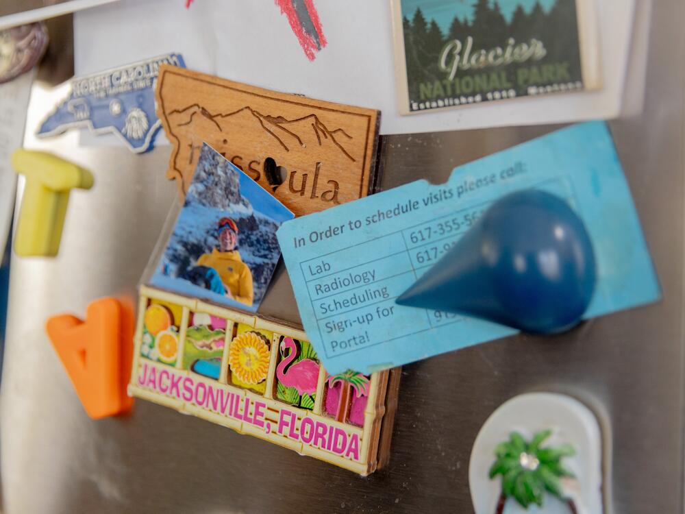 A scheduling card for medical appointments appears among vacation magnets on Logan's family fridge.