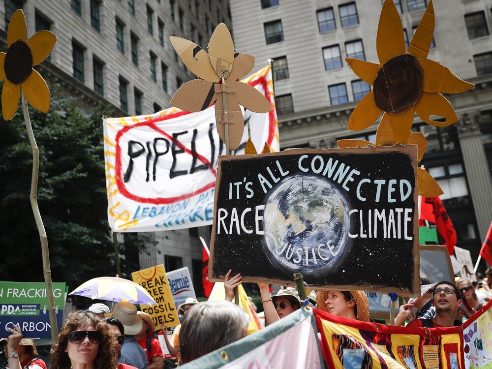 Climate change activists carry signs as they march during a protest in Philadelphia in 2016. Earlier that year, U.S. prosecutors allege hackers began targeting prominent American climate activists in an effort to gather information to foil lawsuits against the fossil fuel industry over damage communities have faced from global warming.<br><br>