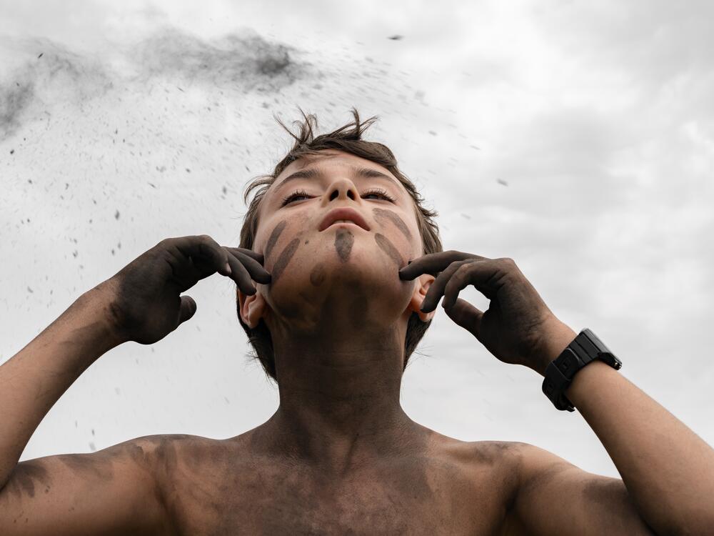Arturo paints his face with campfire ashes at a nature immersion camp in Italy.