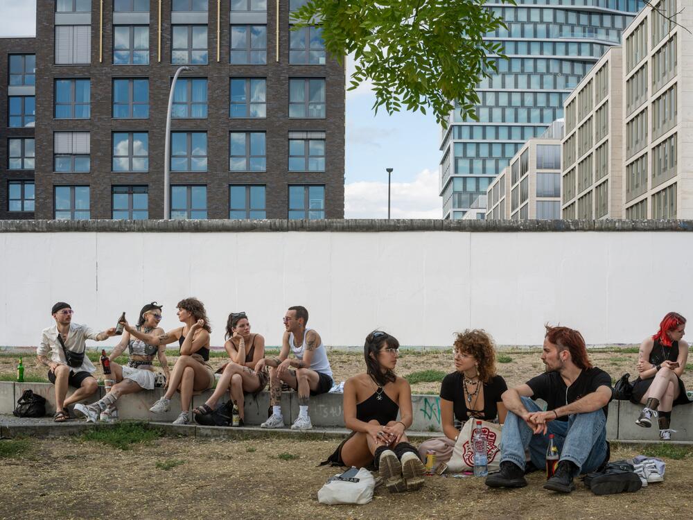 Foglia followed butterflies to the green spaces where they paused—some of which were marked by human borders. Here, decorated young people sit at the Berlin Wall on a Sunday morning, just out of all-night clubs.
