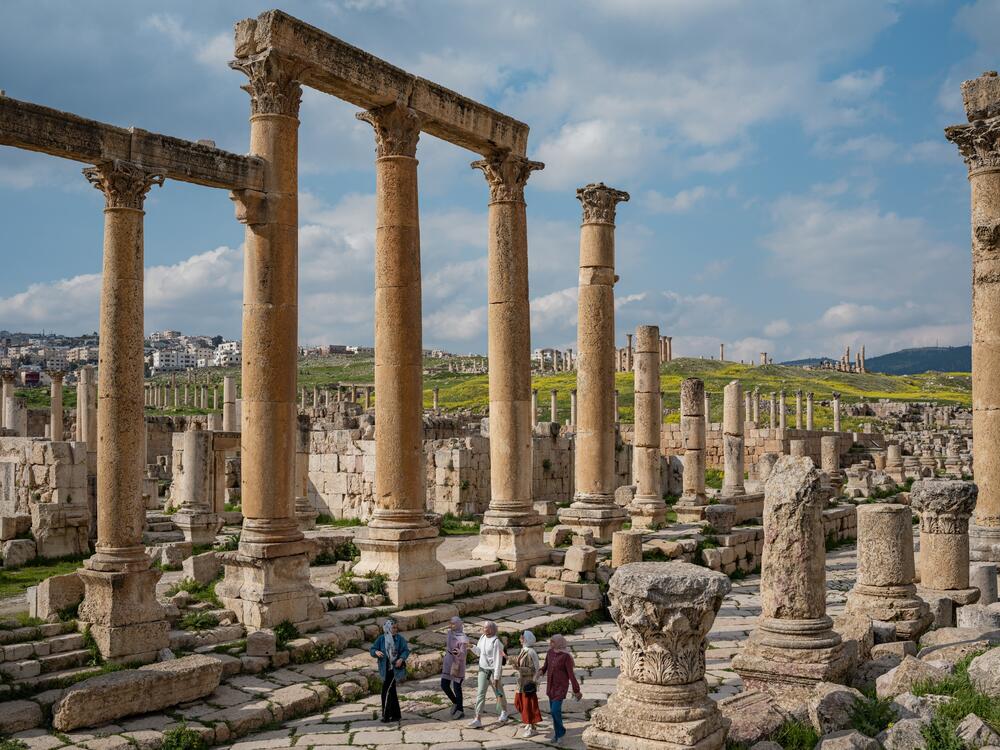 Palestinian refugees Ghina, Raghad, Yusra, Nahla, and Rahaf walk through Roman Ruins in Jordan. Painted lady butterflies have been migrating through these blooming fields for millions of years.