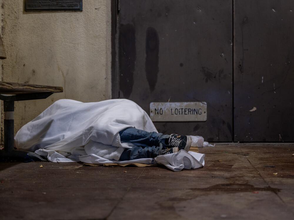 An unhoused resident sleeps on a dimly lit porch on the steps of a school in Austin. This week, all staff  at the United States Interagency Council on Homelessness, which coordinates homelessness policy across the federal government, were put on leave.