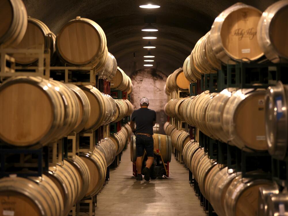 A worker pushes a wine barrel into a storage facility at Hunnicutt winery in St. Helena, Calif., on Sept. 30, 2021.