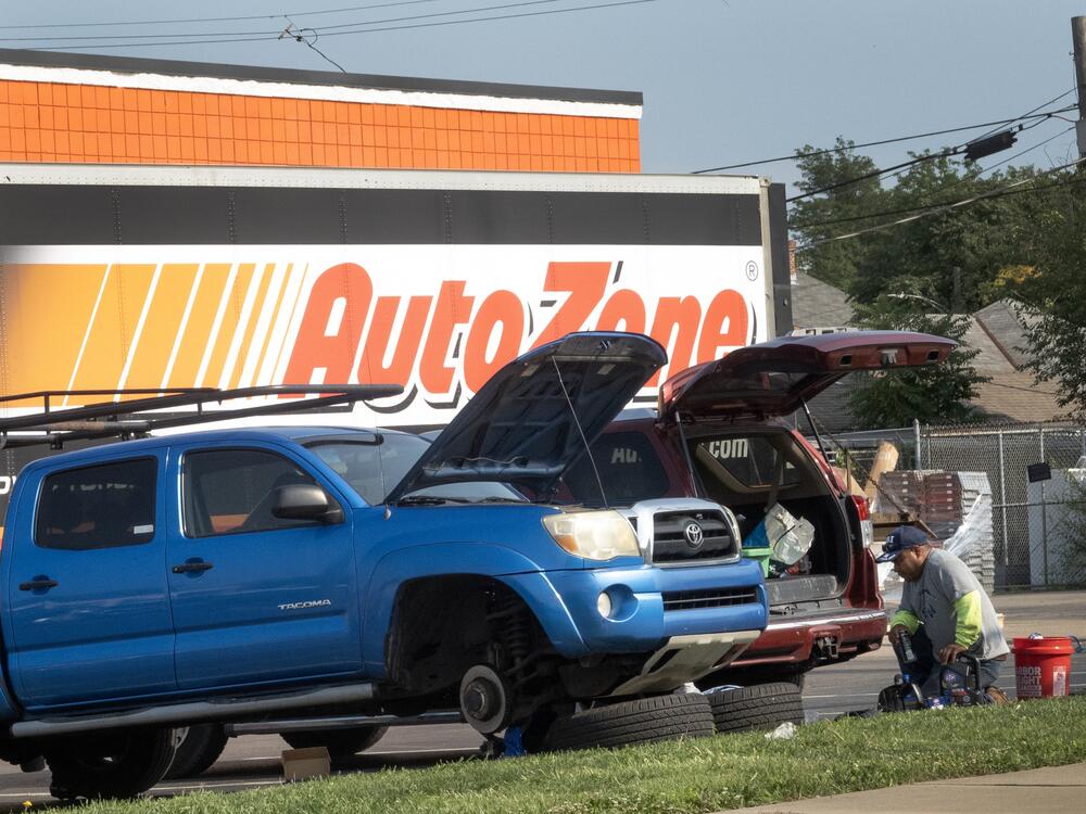 Men repair the brakes on a truck in the parking lot of an auto parts store in Middletown, Ohio, in 2024. Prices of car parts, car repairs and car insurance are expected to rise if tariffs remain in place.