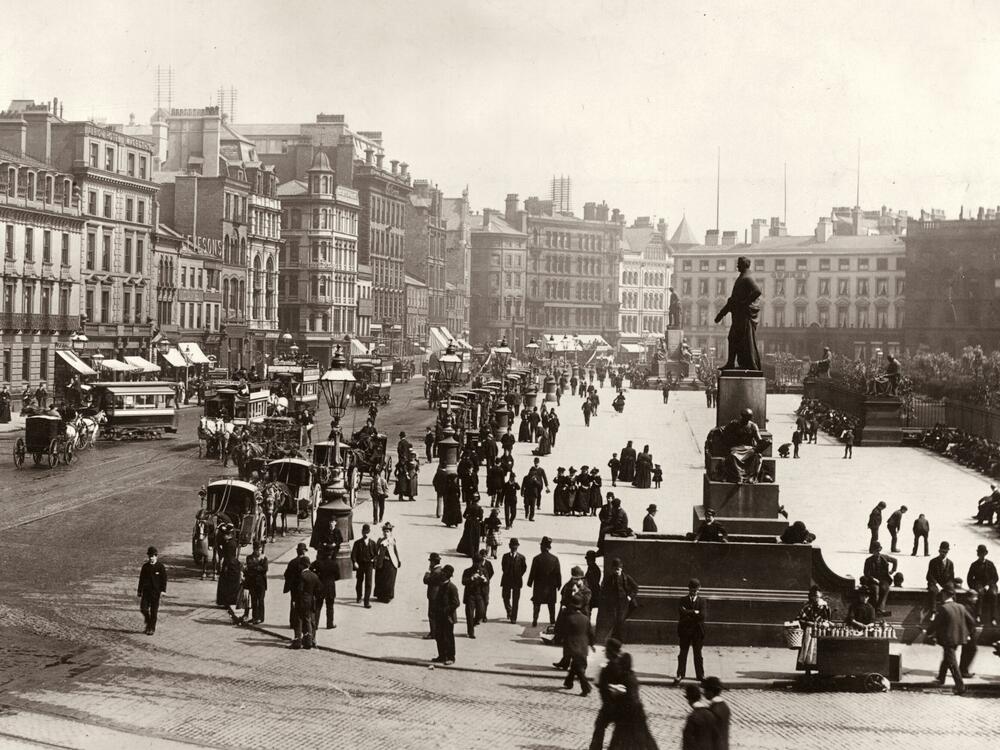People and horse-drawn carriages are seen in Manchester circa 1880.