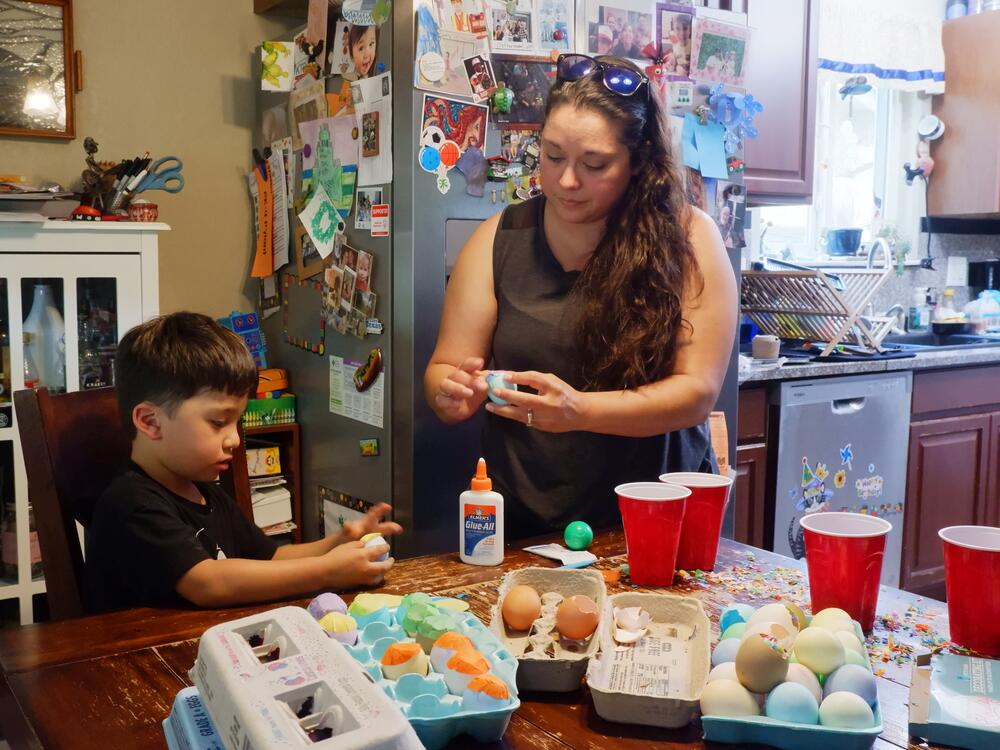 Denise Solis shows her four-year-old son Noah Solis how to seal a cascaron (confetti-filled egg) with tissue paper.