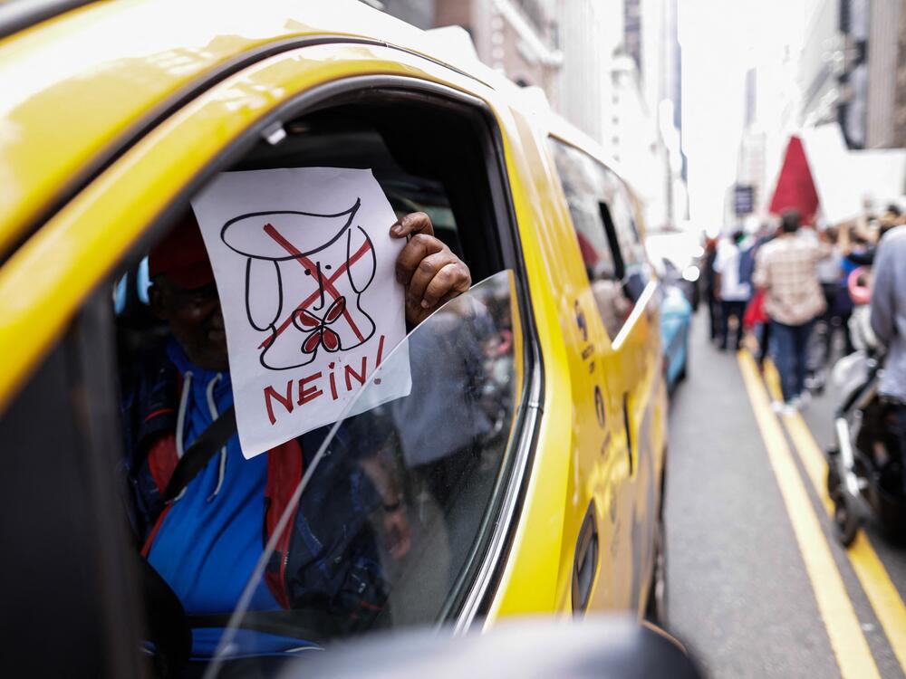 A yellow cab driver holds a sign as people march during a rally titled 