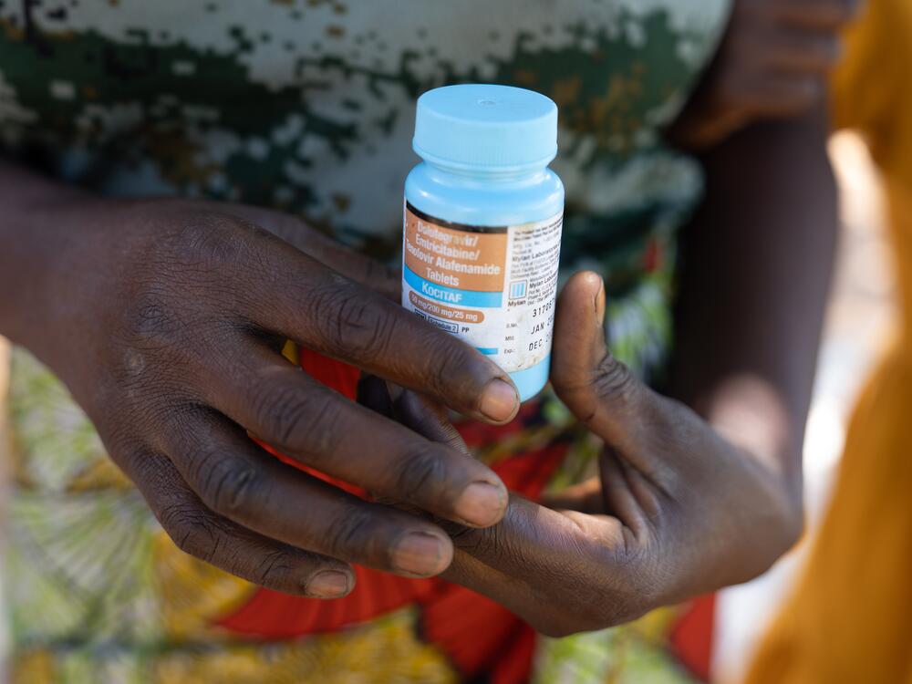 Theresa Mwanza, a single mom, holds an empty bottle of her HIV medicine.