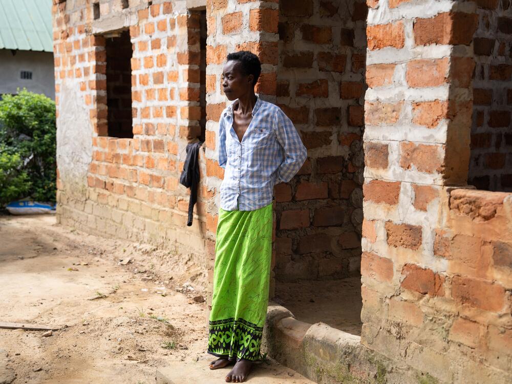 Mary stands outside the family compound that she shares with her mother, her four children, her two sisters and their children.