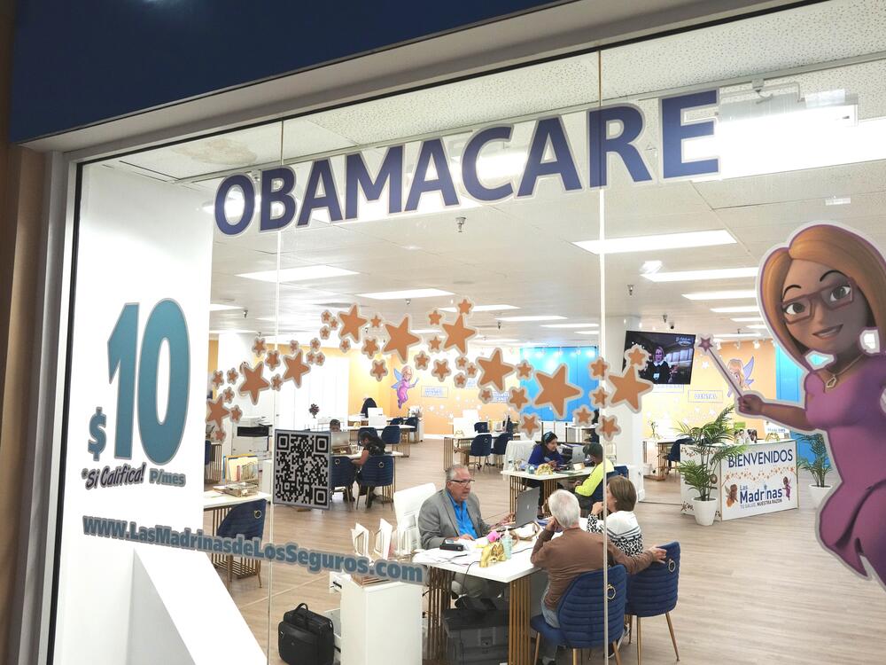 An insurance agent talks with clients inside a shopping center in Miami, on Dec. 5, 2023. Once someone enrolls in an Affordable Care Act plan, they can get help with sticky insurance issues from caseworkers at the federal government. Many caseworkers were cut in the recent round of federal layoffs.