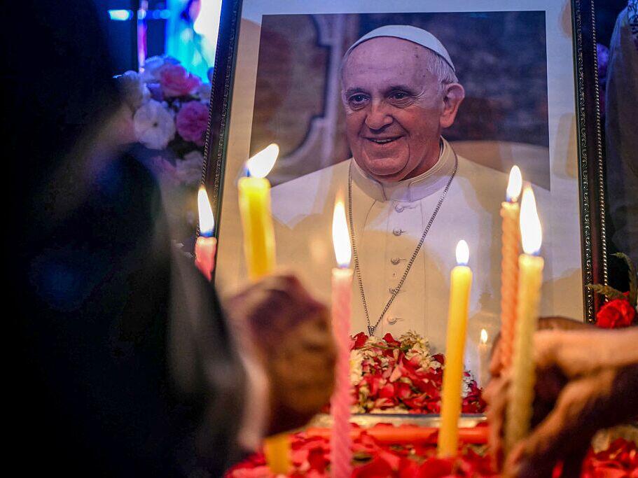 People light candles as they pay respects in front of a portrait of Pope Francis on Monday during a condolence meeting in New Delhi.