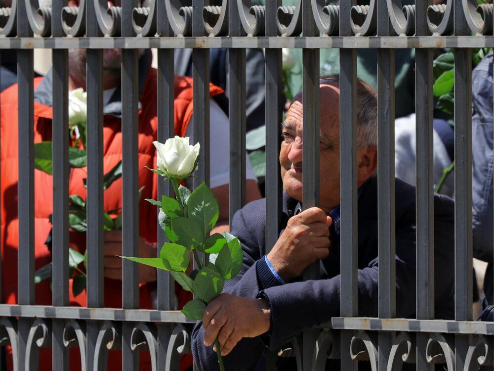 A man holds a rose outside the Papal Basilica of Saint Mary Major, on the day of the funeral of Pope Francis,.