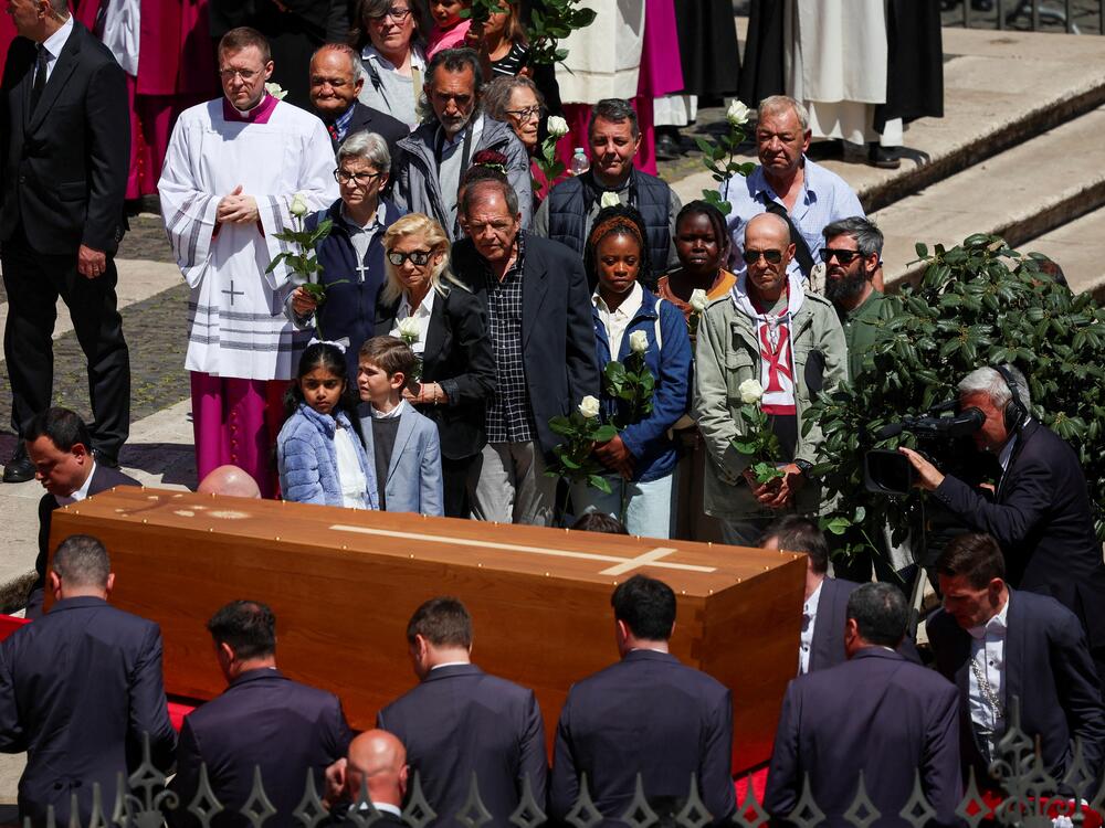People hold white roses as pallbearers carry the coffin of Pope Francis inside the Papal Basilica of Saint Mary Major.