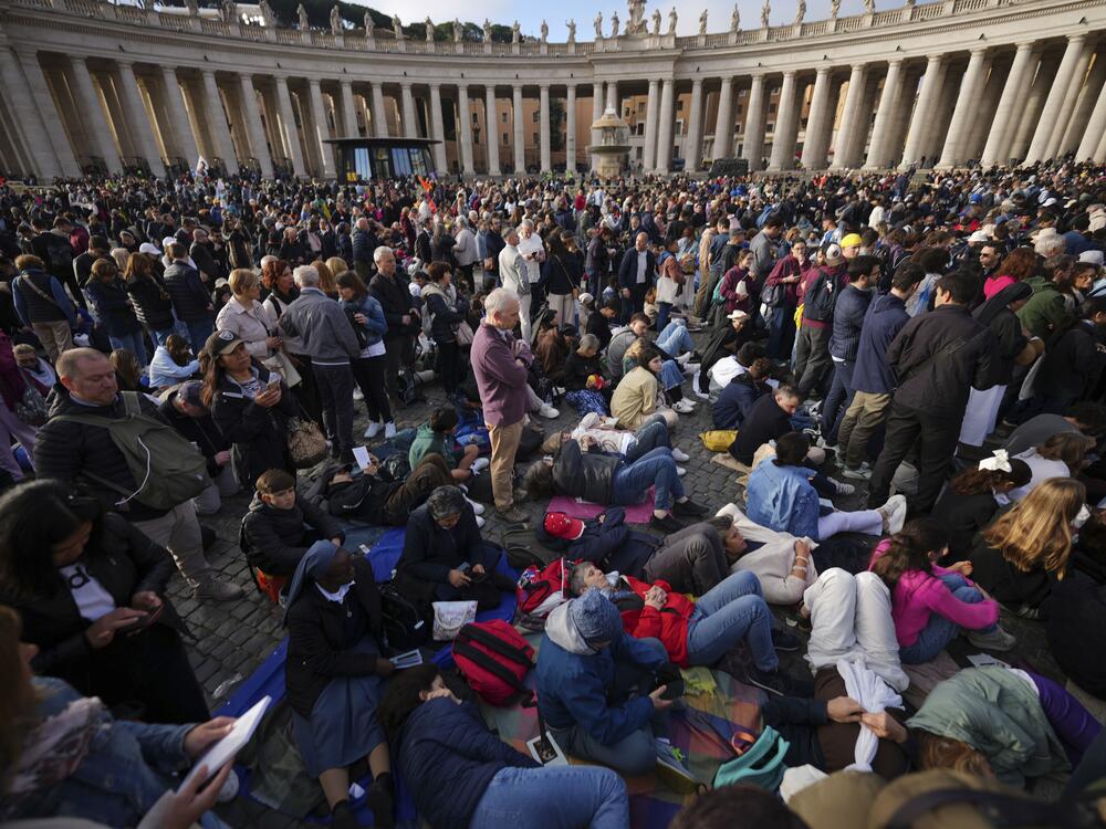 Faithful rest on the ground ahead of the funeral of Pope Francis in St. Peter's Square at the Vatican.