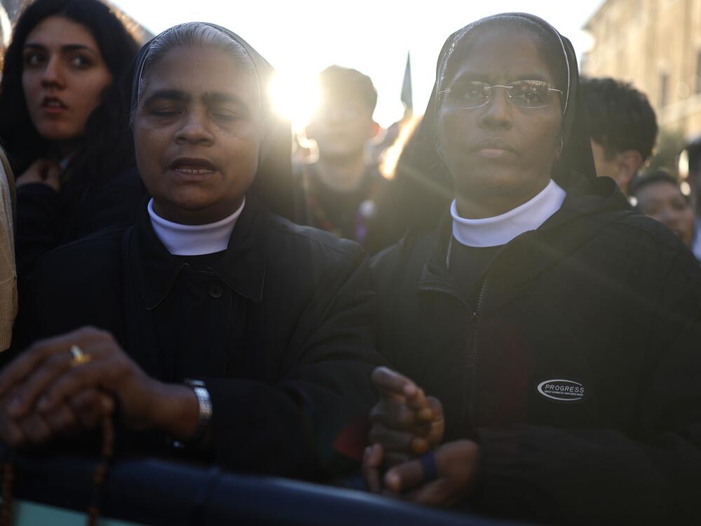 Two nuns look on as people gather during the funeral of Pope Francis in St. Peter's Square.
