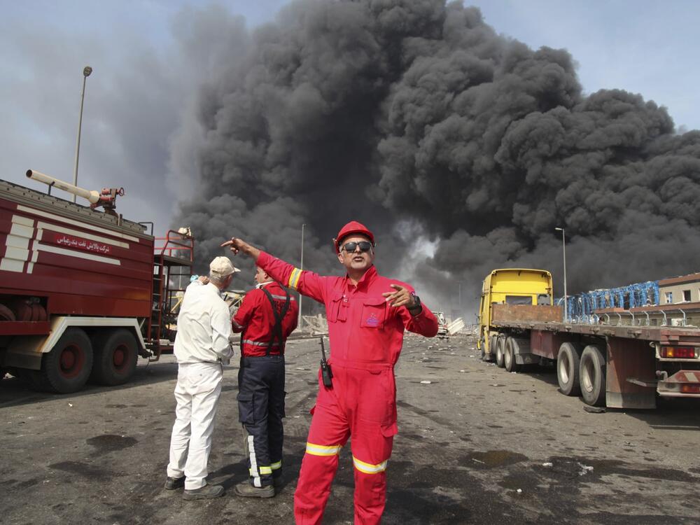 In this photo provided by Islamic Republic News Agency (IRNA), firefighters work as black smoke rises in the sky after a massive explosion rocked a port near the southern city of Bandar Abbas, Iran on Saturday.