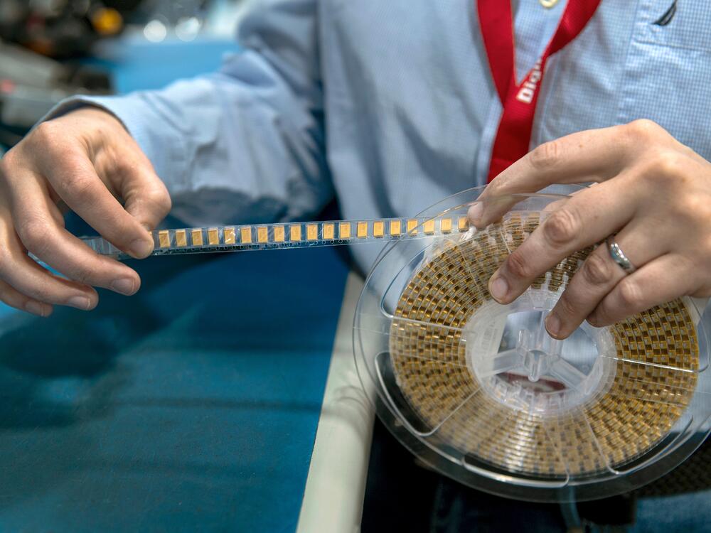 A DigiKey employee unspools a reel of individual electronic components.