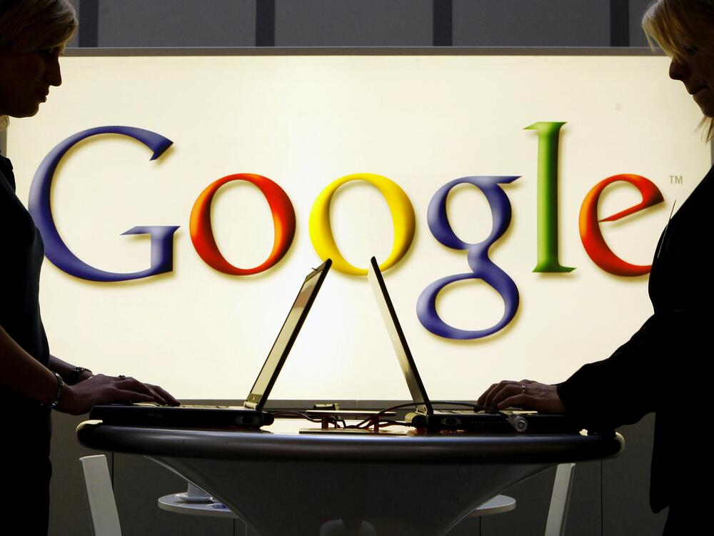 Exhibitors work on laptop computers in front of an illuminated sign of the Google logo in 2007. The Justice Department's antitrust lawsuit against Google marks the government's most significant attempt to protect competition since its groundbreaking case against Microsoft more than 20 years ago.