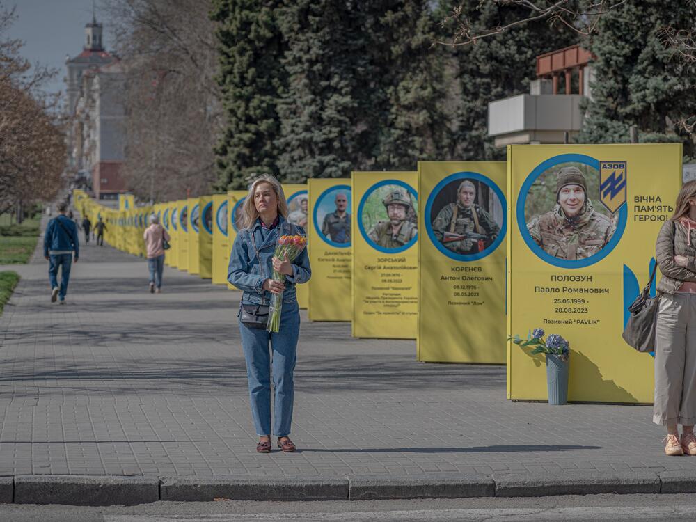 People walk down the street past banners commemorating fallen soldiers in Zaporizhzhia.