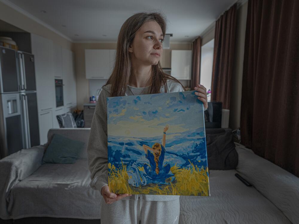 Alyona Serdyuk holds a painting with Ukraine's flag colors at home in Zaporizhzhia.