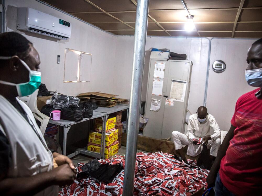 Medics from Doctors without Borders in Nigeria stand by stacks of Plumpy'Nut, which is used to treat severely malnourished children.