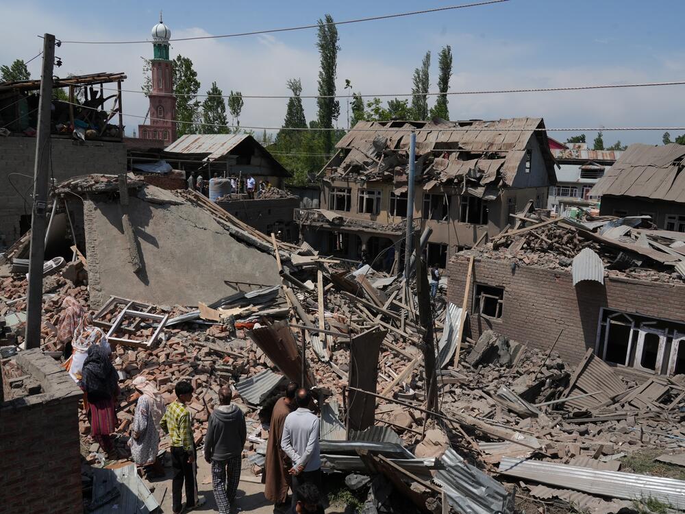 People stand near the razed house of alleged Kashmiri militant Ahsan Ul Haq Sheikh's family house in Murran area of Pulwama district on April 26, 2025.