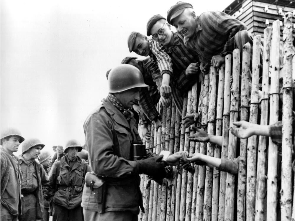A still from a documentary film shows a U.S. soldier reaching out to outstretched hands of prisoners of the liberated Nazi concentration camp at Dachau, in then West Germany, in April 1945, during World War II.
