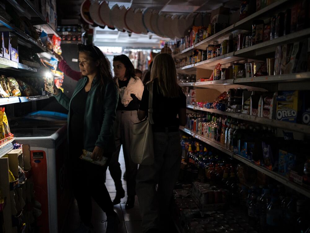 People shop for groceries using their phone as flashlight in Madrid, Spain on April 28.