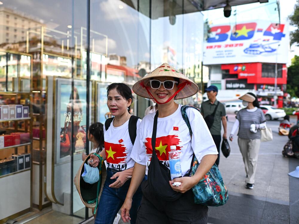 Women wearing Vietnamese national flag T-shirts walk past the Saigon Centre shopping complex in Ho Chi Minh City on April 29, 2025, ahead of celebrations to mark the 50th anniversary of the end of the Vietnam War.