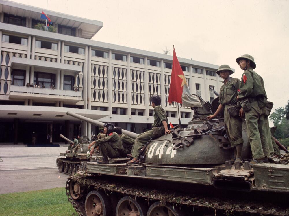 Victorious North Vietnamese troops on tanks take up positions outside Independence Palace in Saigon on April 30, 1975, the day the South Vietnamese government surrendered, ending the Vietnam War. Communist flags fly from the palace and the tank.