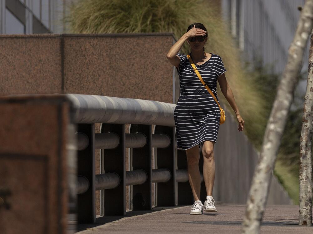 A woman shields her eyes from the sun as she walks in downtown Los Angeles during a heatwave Friday, Sept. 6, 2024.