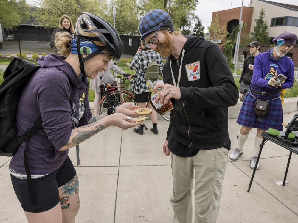 Volunteer Lance Poehler (blue cap) provides plates of fresh-cooked pancakes for people who want to stop and eat, but some, like commuter Leah Brown, take theirs to go.
