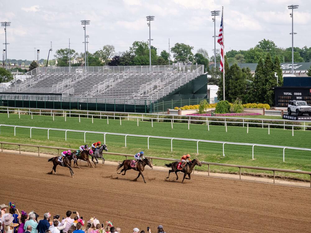 Spectators watch a horse race at Churchill Downs in Louisville, Ky., on April 30, 2025. Junior Alvarado, a jockey from Venezuela, makes his way to second place before crossing the finish line.