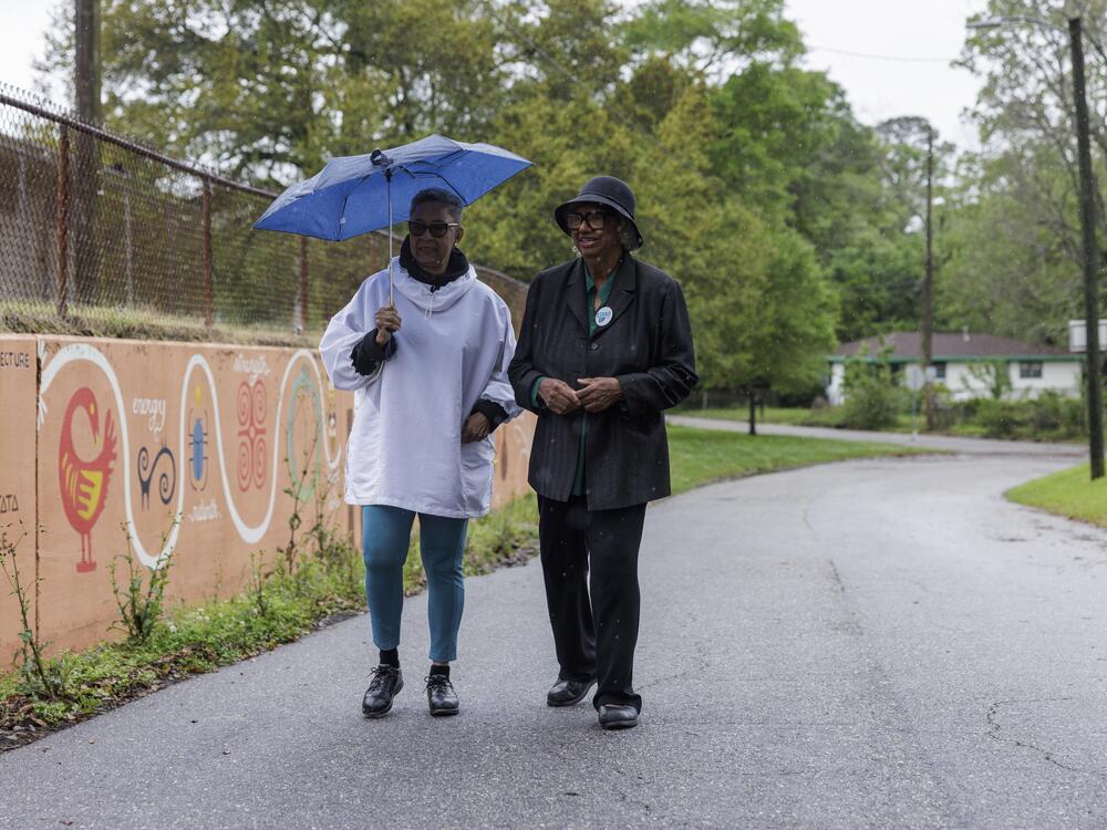 Beverly Cooper (left) and Amelia Bacon walking in the historic Africatown community. They're co-founders of the voter advocacy group Stand Up Mobile.