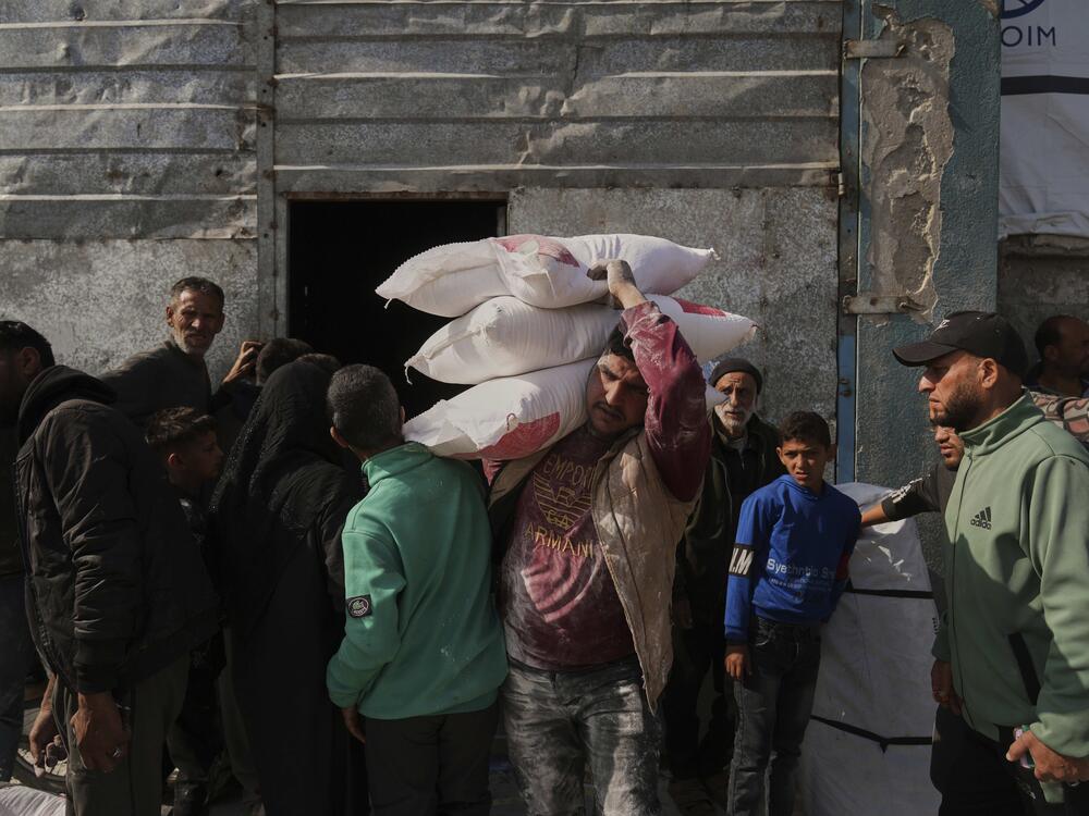 Palestinians receive bags of flour and other humanitarian aid distributed by UNRWA, the U.N. agency helping Palestinian refugees, in Jabaliya, Gaza Strip, on Tuesday.