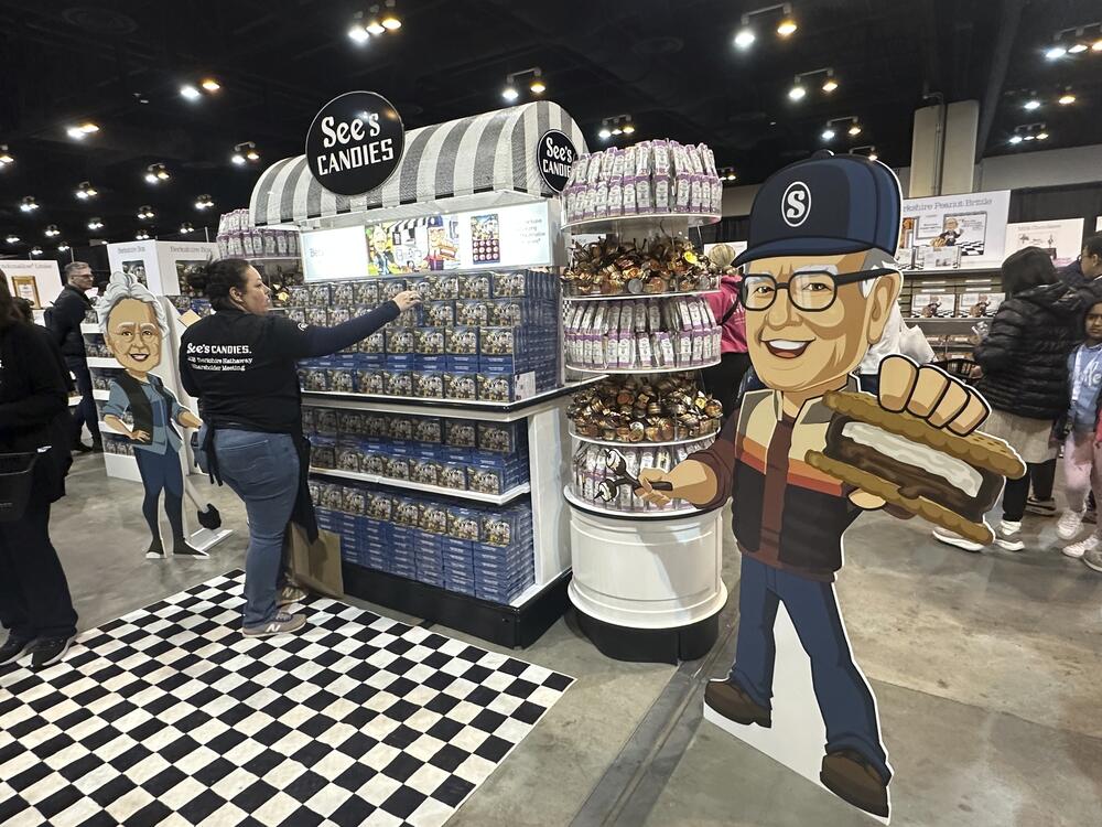 A See's Candies worker restocks the display next to a cutout of Warren Buffett at the Berkshire Hathaway shareholders meeting exhibit hall Friday, May 2, 2025 in Omaha, Neb. (AP Photo/Josh Funk)