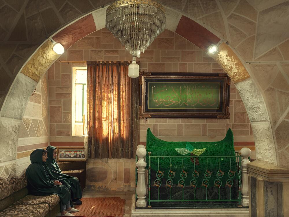 Two women sit at the Druze's Ayn Zaman shrine. The Druze hold that members of their faith who die suddenly — including being murdered or killed by accident — are immediately reincarnated as newborn babies.