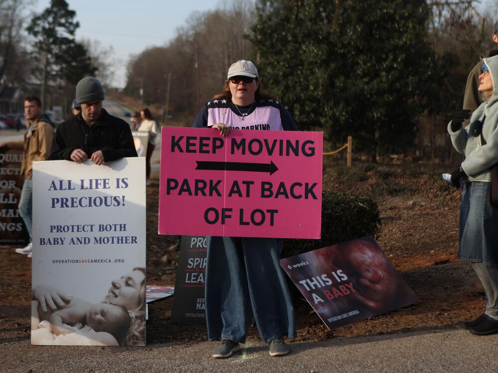 A clinic escort directs patients where to park as anti-abortion activists protest in front of the Greenville Women's Clinic.