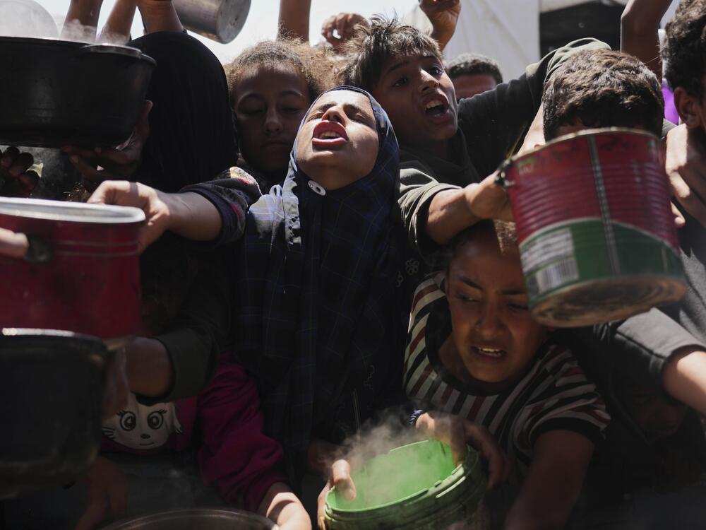 Palestinians struggle to get donated food at a community kitchen in Khan Younis, Gaza Strip, Monday.