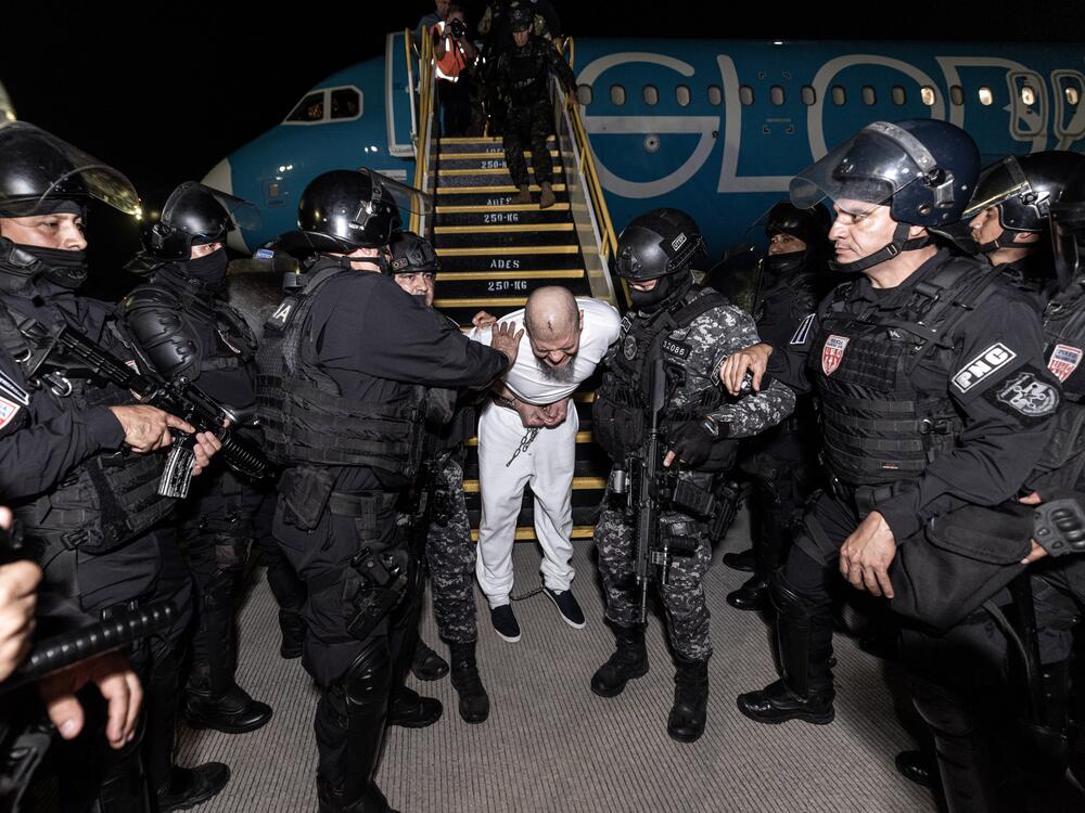 Guards escort one of the hundreds of alleged members of the 'Tren De Aragua' and Mara Salvatrucha gangs who were deported from the U.S. to El Salvador.
